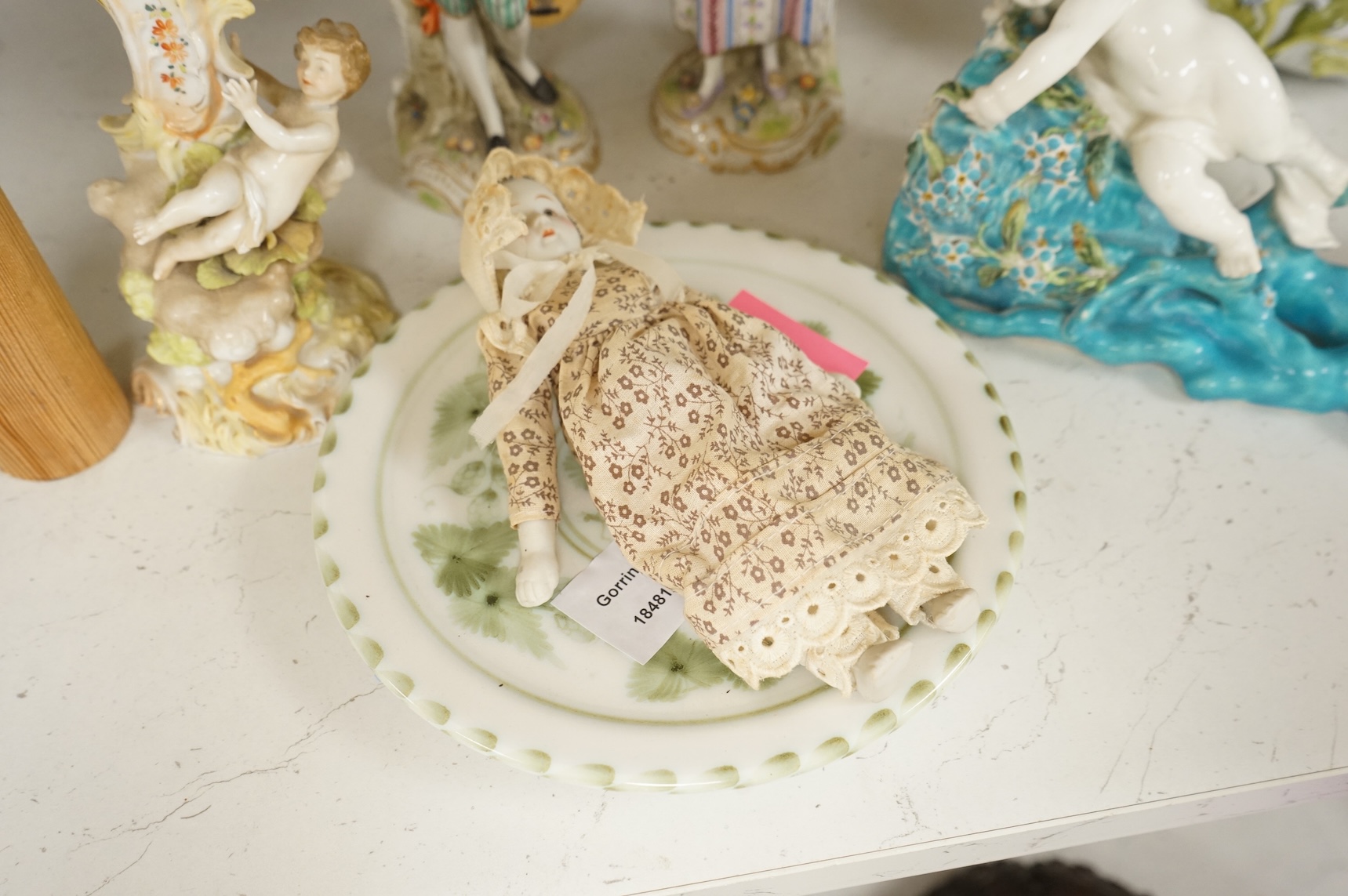 A pair of Sitzendorf figurines, damage to one, a pair of candlesticks, a Rye pottery dish, a Moore Bros. wall pocket, a doll and a basket, tallest 22.5cm
